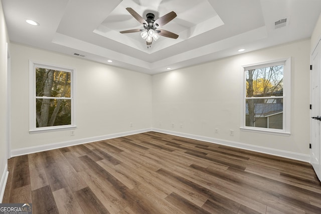 unfurnished room featuring a raised ceiling, ceiling fan, and dark wood-type flooring