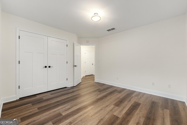 unfurnished bedroom featuring dark wood-type flooring and a closet