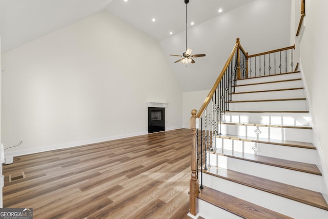 stairs featuring hardwood / wood-style flooring, ceiling fan, and high vaulted ceiling