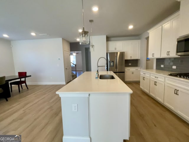 kitchen with white cabinetry, stainless steel appliances, and a center island with sink