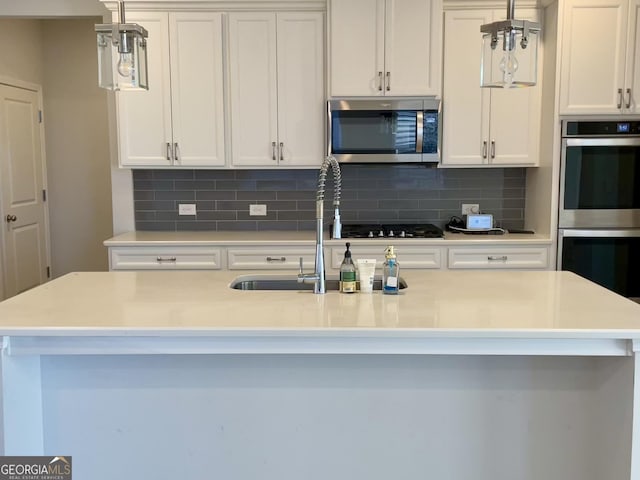 kitchen with white cabinetry, appliances with stainless steel finishes, and a center island with sink