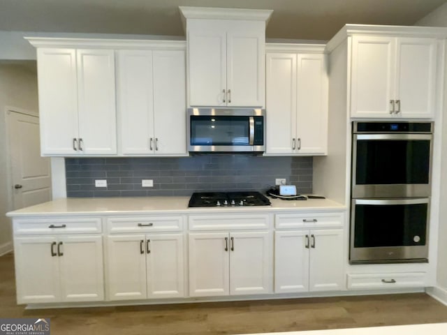 kitchen featuring white cabinetry, tasteful backsplash, stainless steel appliances, and light wood-type flooring