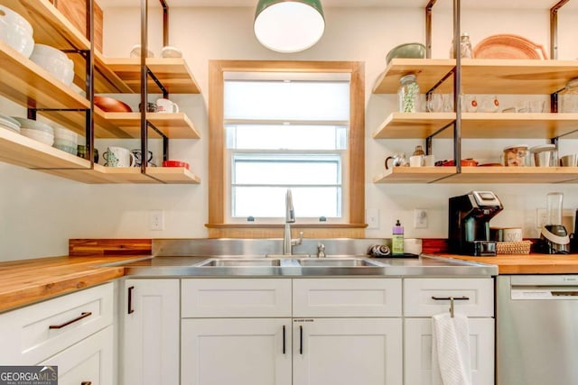 kitchen with stainless steel dishwasher, stainless steel counters, white cabinets, and sink