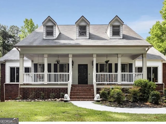 cape cod home with covered porch and a front yard