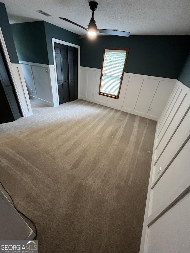 unfurnished bedroom with a textured ceiling, light colored carpet, and ceiling fan