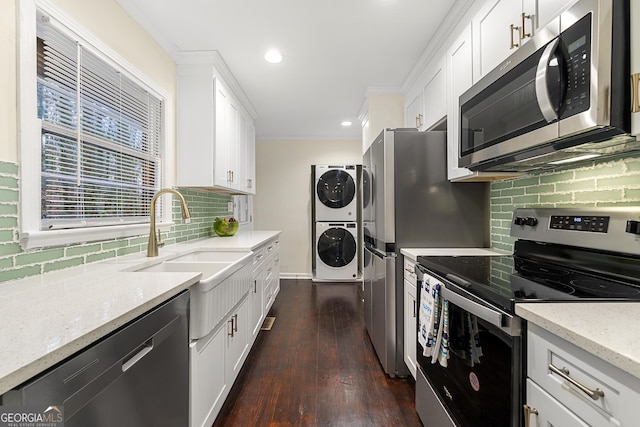 kitchen featuring stacked washer and clothes dryer, sink, white cabinetry, light stone counters, and appliances with stainless steel finishes