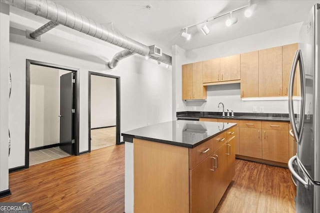 kitchen with stainless steel fridge, a center island, light hardwood / wood-style floors, and sink