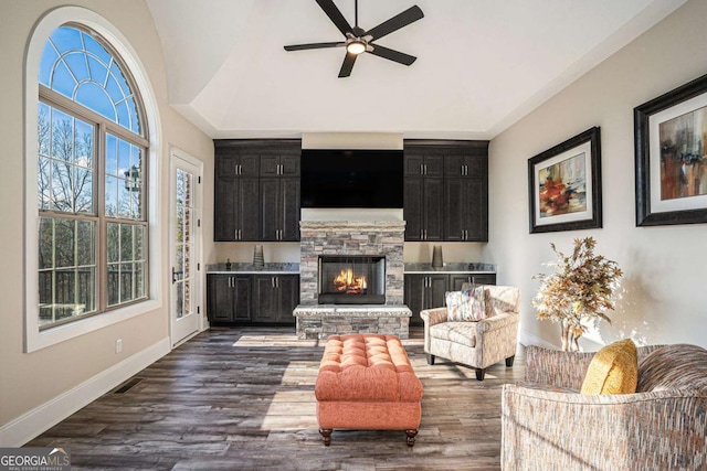 living room featuring ceiling fan, dark hardwood / wood-style flooring, and a fireplace