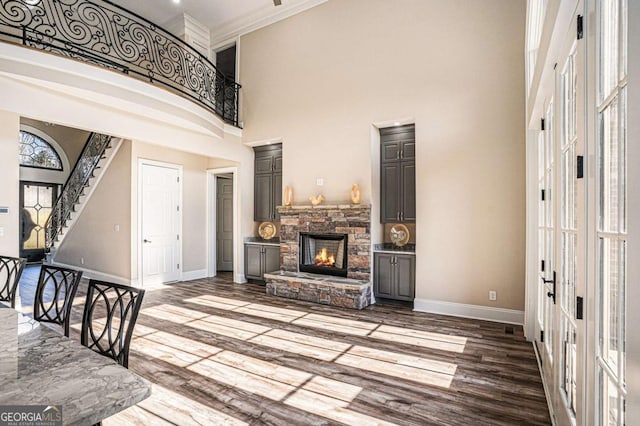 interior space featuring a towering ceiling, a stone fireplace, a wealth of natural light, and ornamental molding