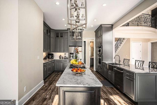 kitchen with dark wood-type flooring, light stone counters, gray cabinets, a kitchen island, and appliances with stainless steel finishes