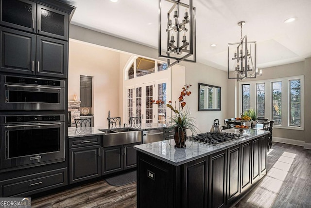 kitchen featuring light stone countertops, a kitchen island, dark hardwood / wood-style floors, and appliances with stainless steel finishes