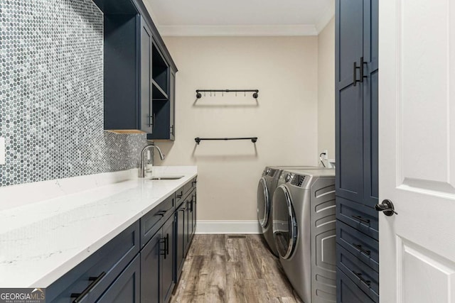 laundry area featuring sink, cabinets, ornamental molding, washer and dryer, and hardwood / wood-style flooring