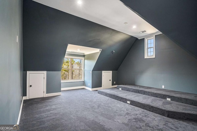 additional living space featuring a wealth of natural light, dark carpet, and vaulted ceiling