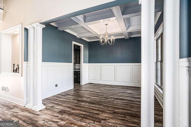 unfurnished dining area featuring beam ceiling, coffered ceiling, dark hardwood / wood-style floors, a notable chandelier, and decorative columns