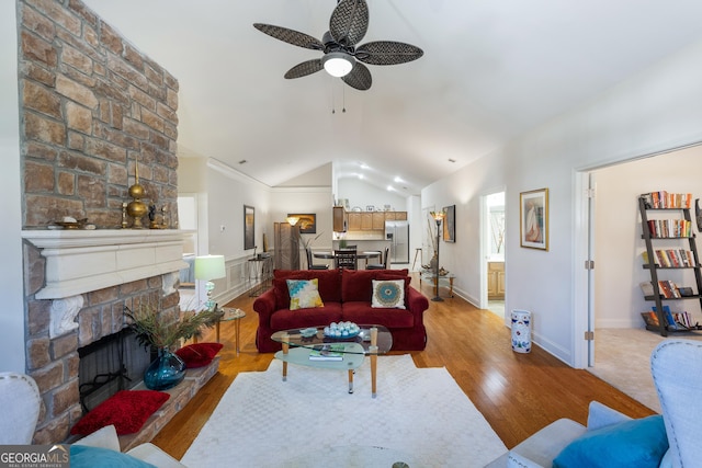 living room with a fireplace, light wood-type flooring, vaulted ceiling, and ceiling fan