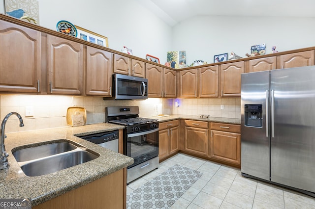 kitchen featuring stainless steel appliances, vaulted ceiling, sink, light tile patterned floors, and stone counters