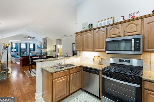 kitchen with kitchen peninsula, appliances with stainless steel finishes, vaulted ceiling, ceiling fan, and sink