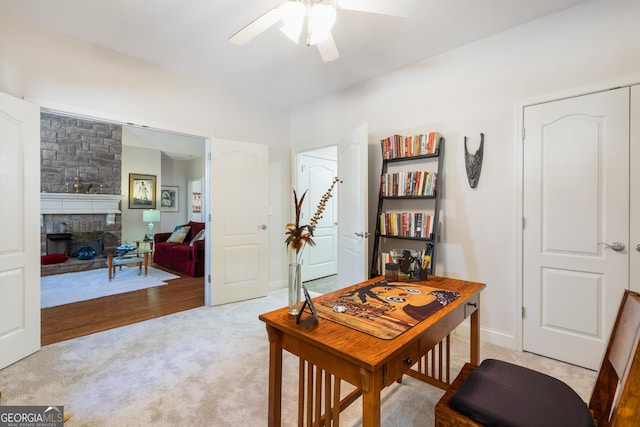 carpeted office space featuring a fireplace and ceiling fan