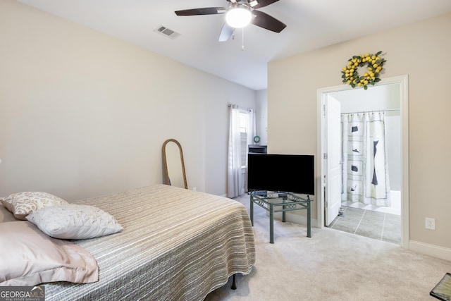 bedroom featuring ceiling fan, light colored carpet, and connected bathroom