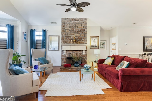 living room with a wealth of natural light, a fireplace, ceiling fan, and hardwood / wood-style flooring