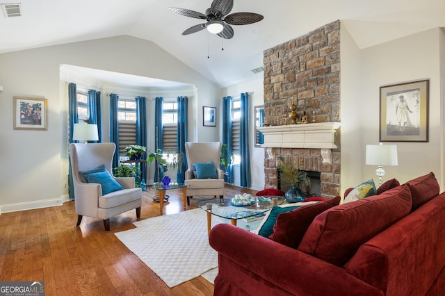 living room with ceiling fan, wood-type flooring, lofted ceiling, and a brick fireplace