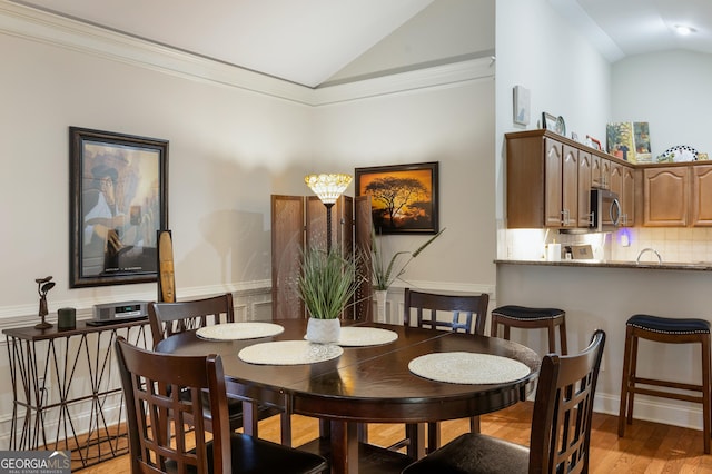 dining space featuring ornamental molding, light hardwood / wood-style floors, and lofted ceiling