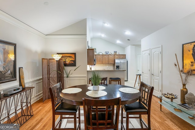 dining space with light hardwood / wood-style flooring, vaulted ceiling, and ornamental molding