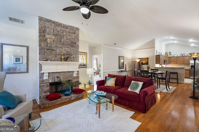 living room featuring ceiling fan, a fireplace, light hardwood / wood-style floors, and lofted ceiling