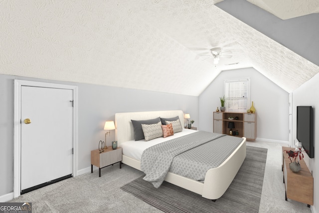 carpeted bedroom featuring ceiling fan, vaulted ceiling, and a textured ceiling