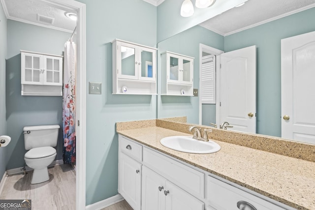 bathroom featuring a textured ceiling, ornamental molding, toilet, and vanity