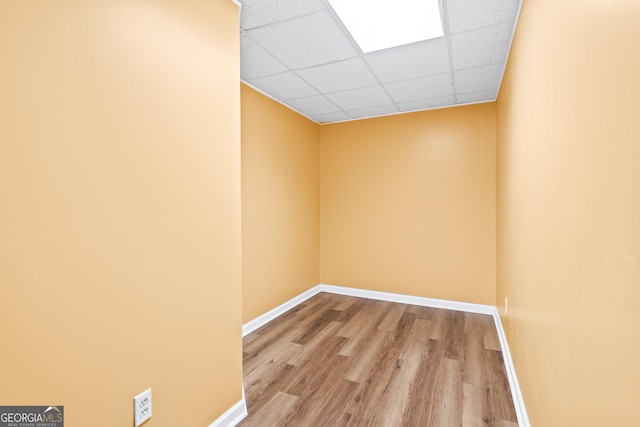 spare room with a paneled ceiling and light hardwood / wood-style flooring