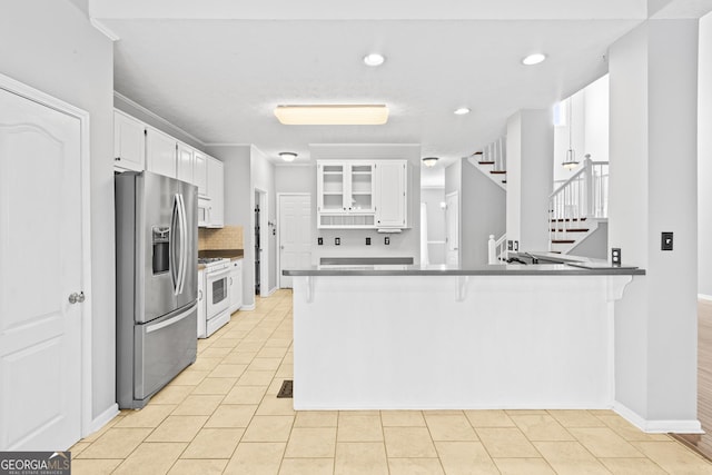 kitchen with white range with gas stovetop, white cabinets, stainless steel fridge with ice dispenser, and kitchen peninsula