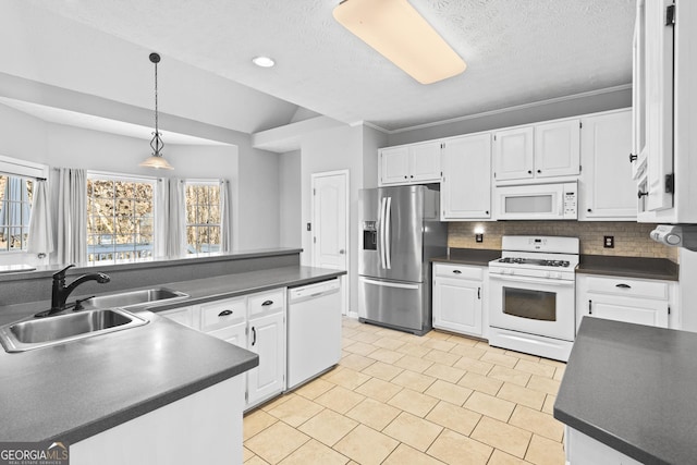 kitchen with white appliances, white cabinets, tasteful backsplash, sink, and vaulted ceiling