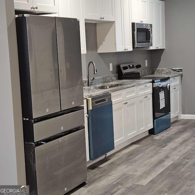 kitchen with light stone counters, white cabinets, and stainless steel appliances