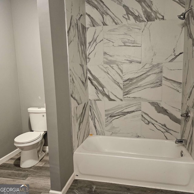 bathroom featuring hardwood / wood-style flooring, tiled shower / bath combo, and toilet