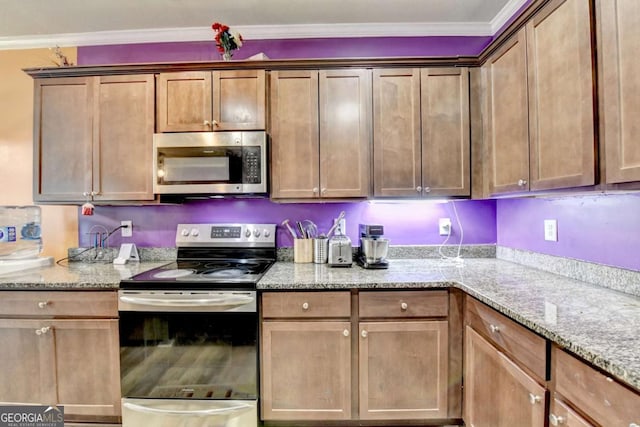 kitchen with light stone counters, crown molding, and stainless steel appliances