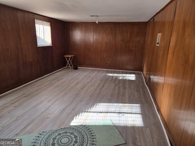 spare room with light hardwood / wood-style flooring and wooden walls