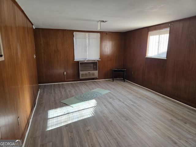 empty room featuring wood walls, light hardwood / wood-style floors, and heating unit