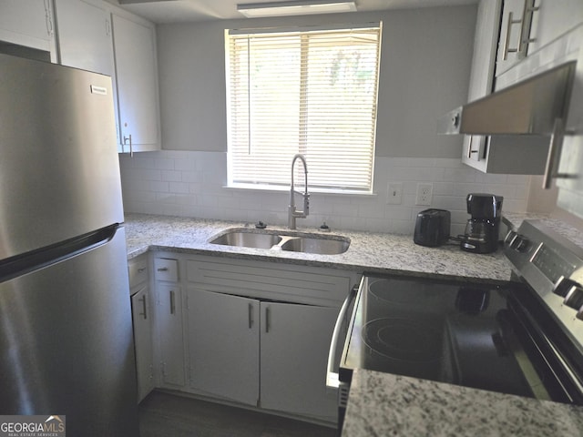 kitchen featuring range, sink, tasteful backsplash, white cabinetry, and stainless steel refrigerator