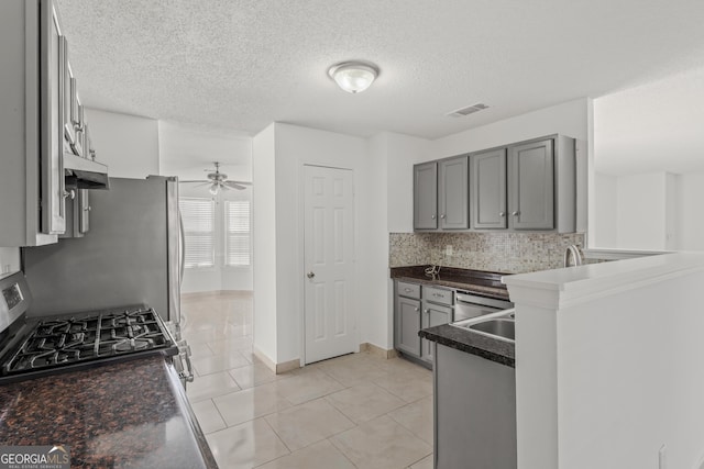 kitchen featuring kitchen peninsula, tasteful backsplash, gas stove, ceiling fan, and light tile patterned floors