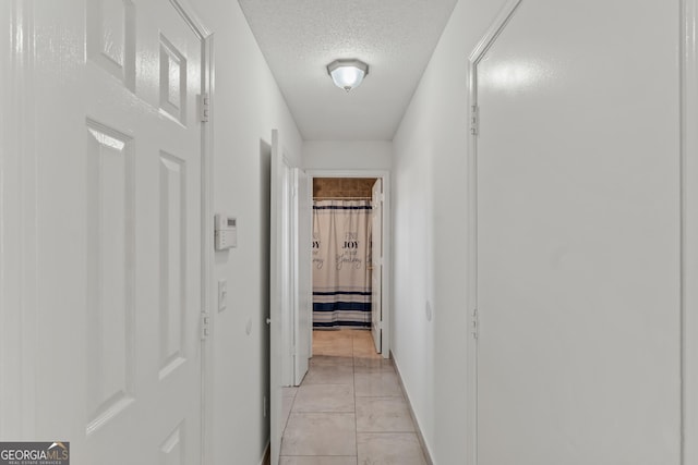 corridor featuring light tile patterned flooring and a textured ceiling