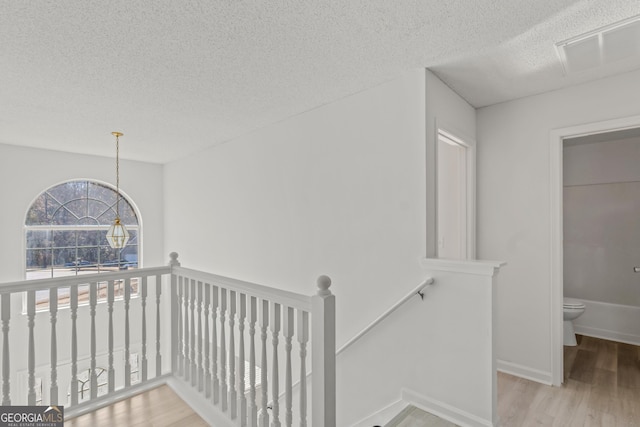 hall with light hardwood / wood-style floors and a textured ceiling