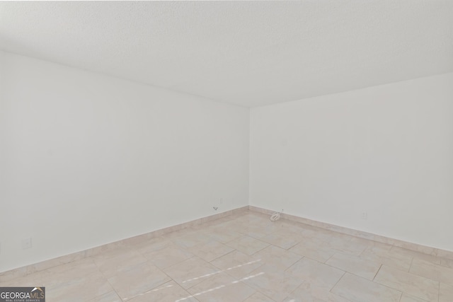 empty room featuring light tile patterned floors and a textured ceiling