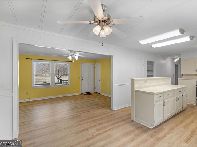 kitchen featuring ceiling fan, a center island, crown molding, white cabinets, and light wood-type flooring