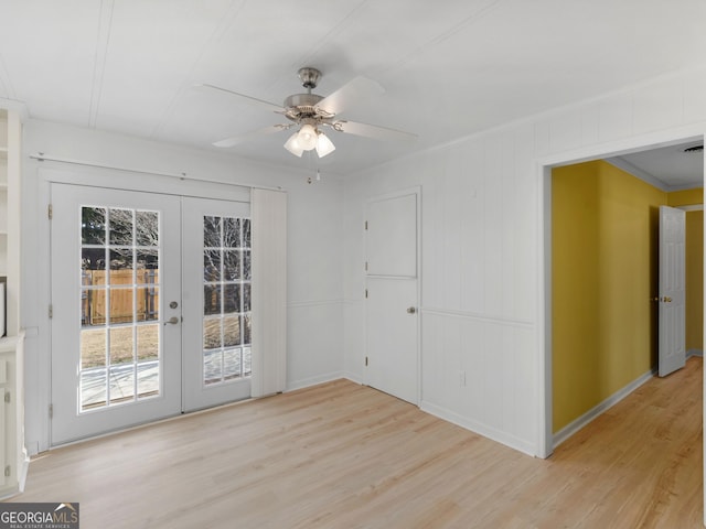 empty room featuring ceiling fan, light hardwood / wood-style floors, ornamental molding, and french doors