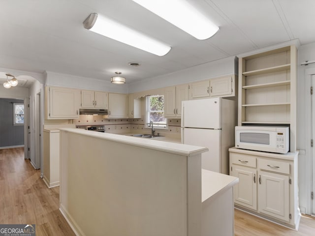 kitchen featuring a center island, sink, light hardwood / wood-style flooring, backsplash, and white appliances