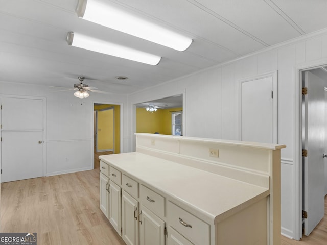 kitchen with light wood-type flooring, ceiling fan, and crown molding