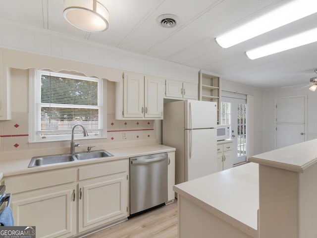 kitchen with backsplash, white appliances, sink, white cabinets, and light hardwood / wood-style floors