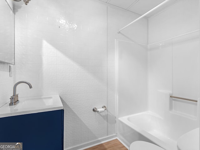 full bathroom featuring vanity, hardwood / wood-style flooring, toilet, tile walls, and tub / shower combination