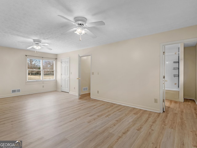 unfurnished room with a textured ceiling, light wood-type flooring, and ceiling fan